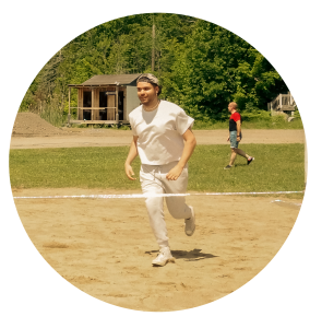 Animateur de camp de jour qui court dans le sable.